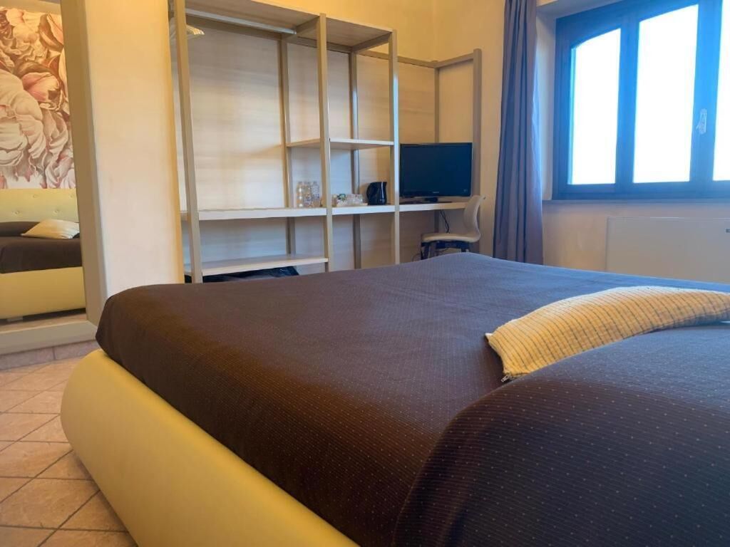 A bedroom with a large bed, a TV on a stand, and a wardrobe.