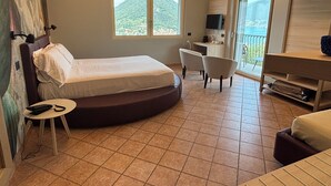Ein Hotelzimmer mit Bett, Schreibtisch, Stuhl, Fernseher und einem Balkon mit Bergblick.