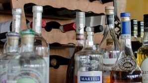 A wooden wine rack with bottles and a wine bottle on a table. - Pernice77 (Sulzano)