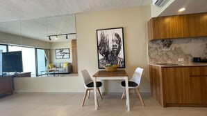 A modern living space with a dining area, kitchen, and a large window.