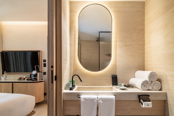 Une salle de bain moderne avec un meuble-lavabo en bois, un grand miroir et des serviettes soigneusement pliées.