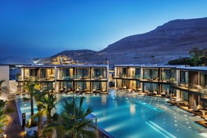 A modern hotel with a large pool, outdoor seating, and a view of the mountains. - Kayma By Isrotel Exclusive (Tamar)