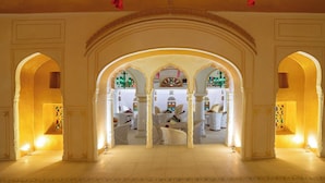 A grand hallway with arches and a view into a room with white furniture and decorative elements. - Medieval Forts, Kalwar, Jaipur (Jaipur)
