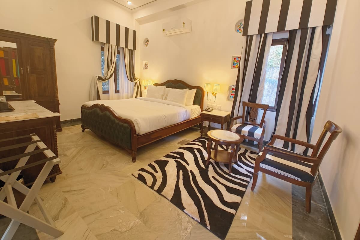 Una habitación de hotel con una cama grande, un escritorio, una silla y un alfombra con estampado de cebra.
