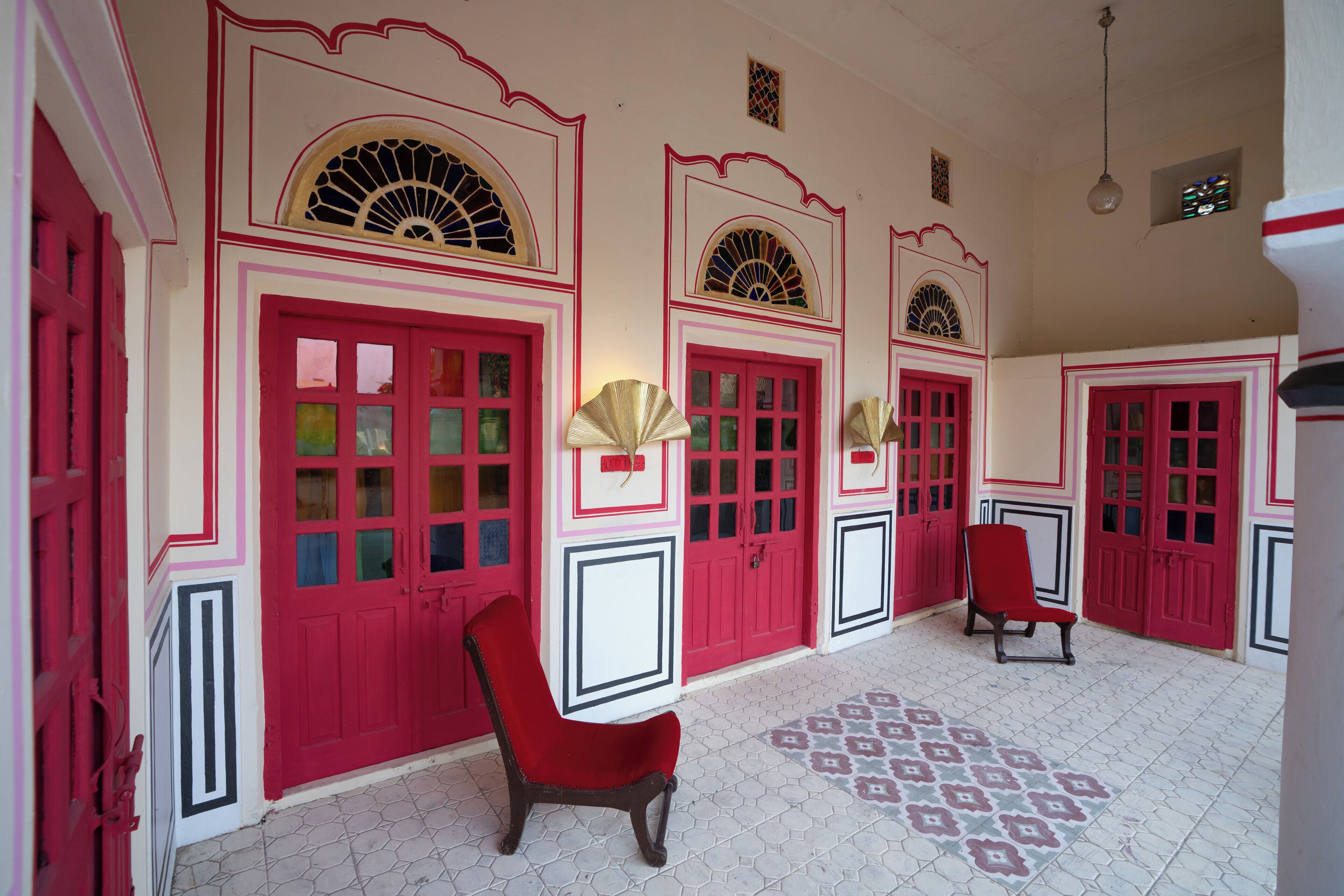 Una habitación con puertas rojas, suelo estampado y una silla roja.