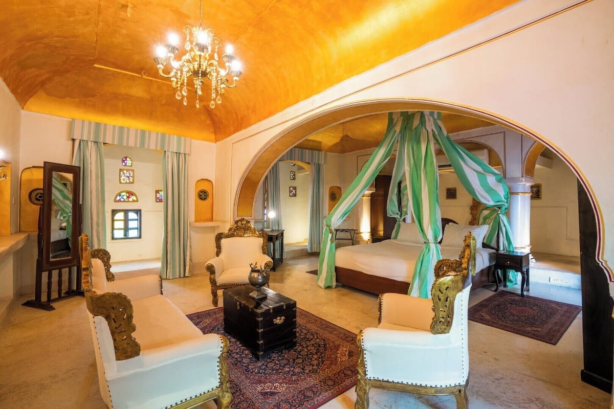 Un dormitorio lujoso con cama con dosel, muebles ornamentales y un candelabro.