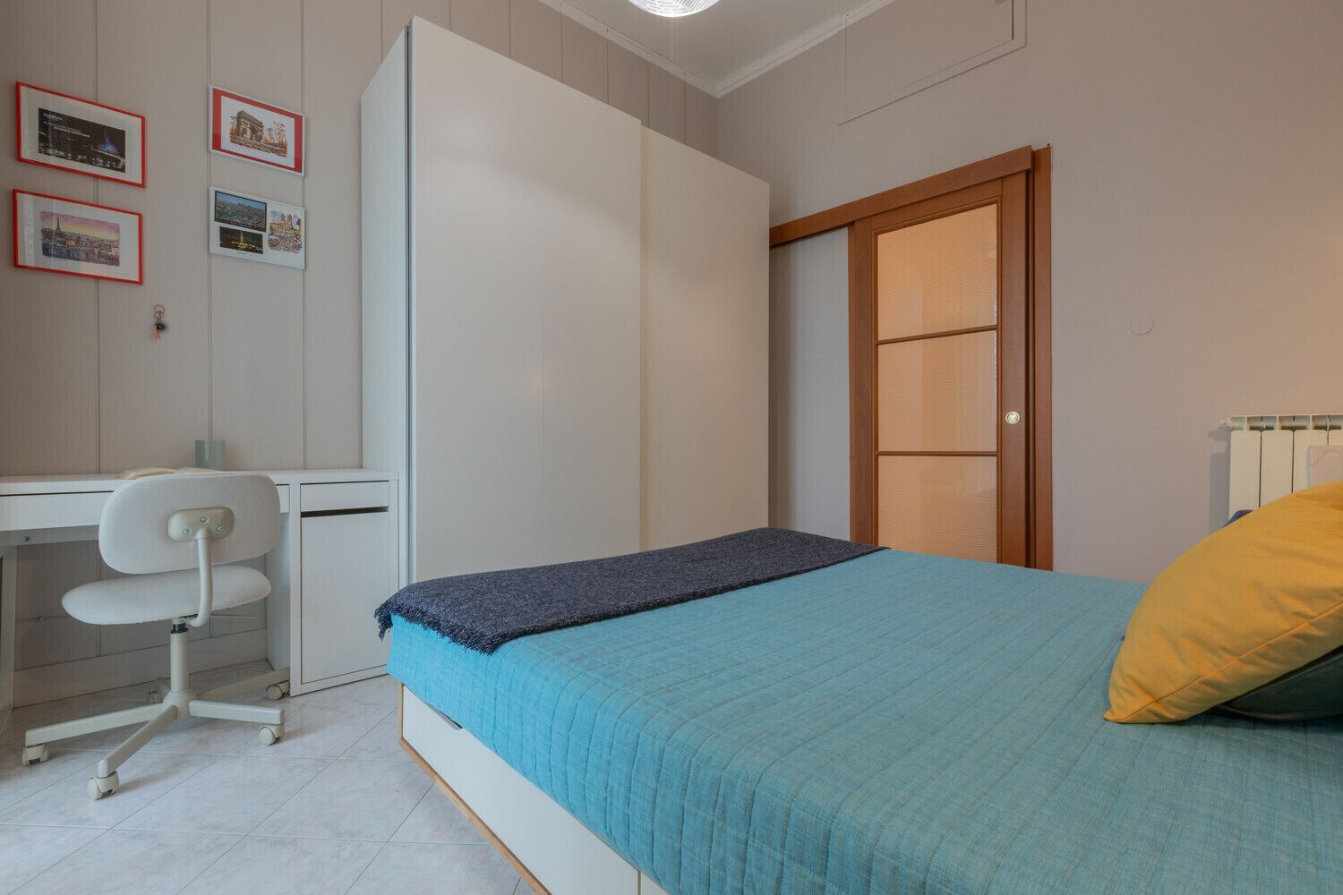 A bedroom with a bed, a desk, and a chair.