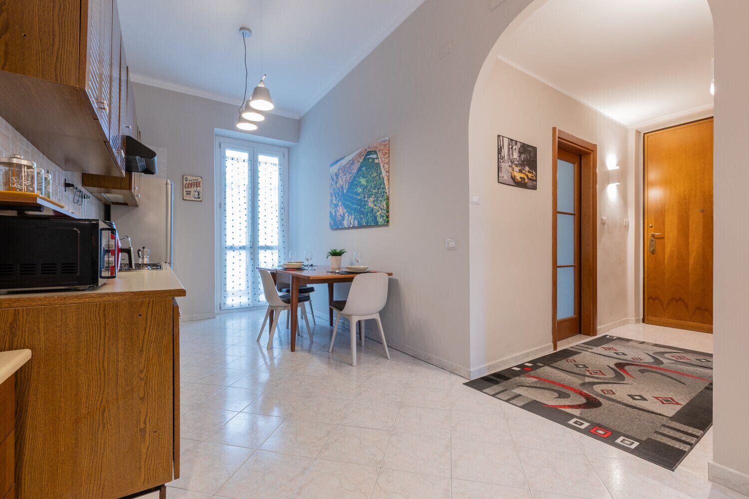 Una cucina moderna con zona pranzo, un'ampia finestra e un ingresso verso un'altra stanza.