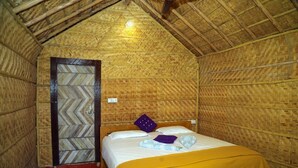A room with a bed, a wooden door, and a thatched roof. - Shanthi Dhama Resort (Koppal)