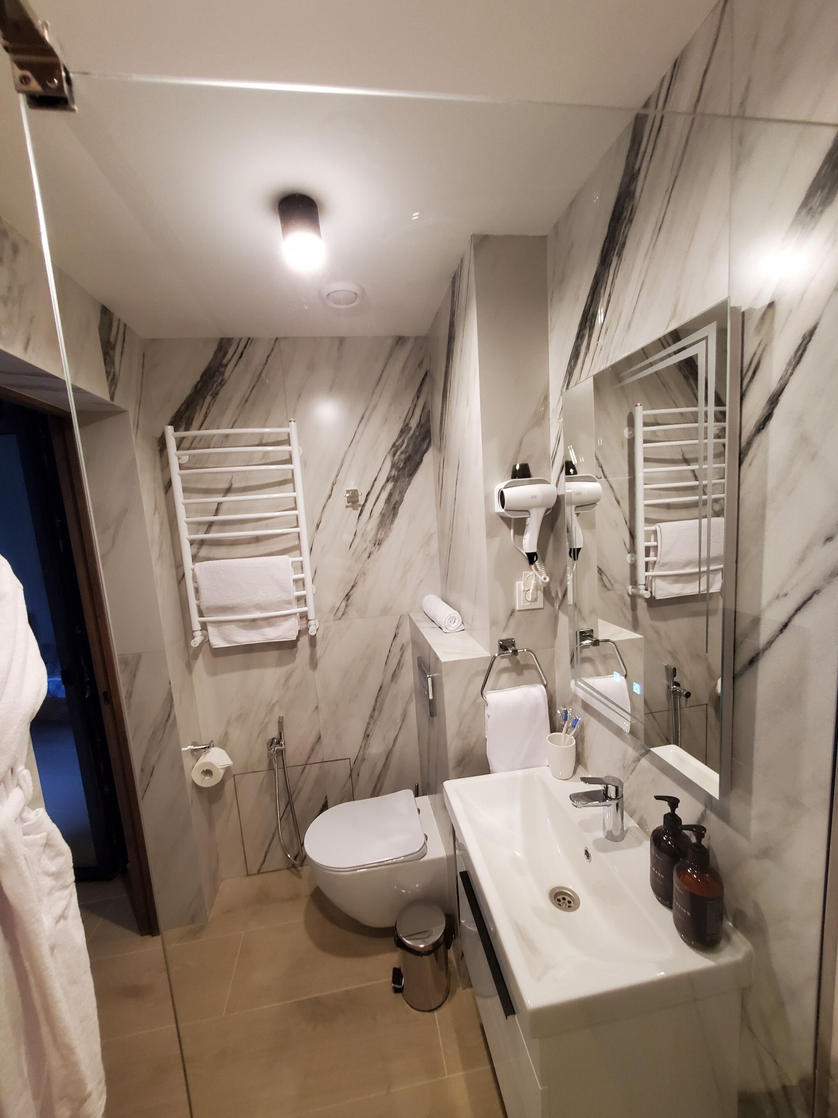 A modern bathroom with a toilet, sink, and mirror.