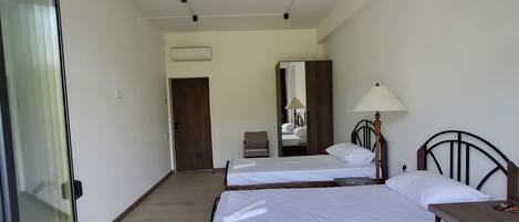 A hotel room with two beds, a desk, a chair, a lamp, and a mirror.