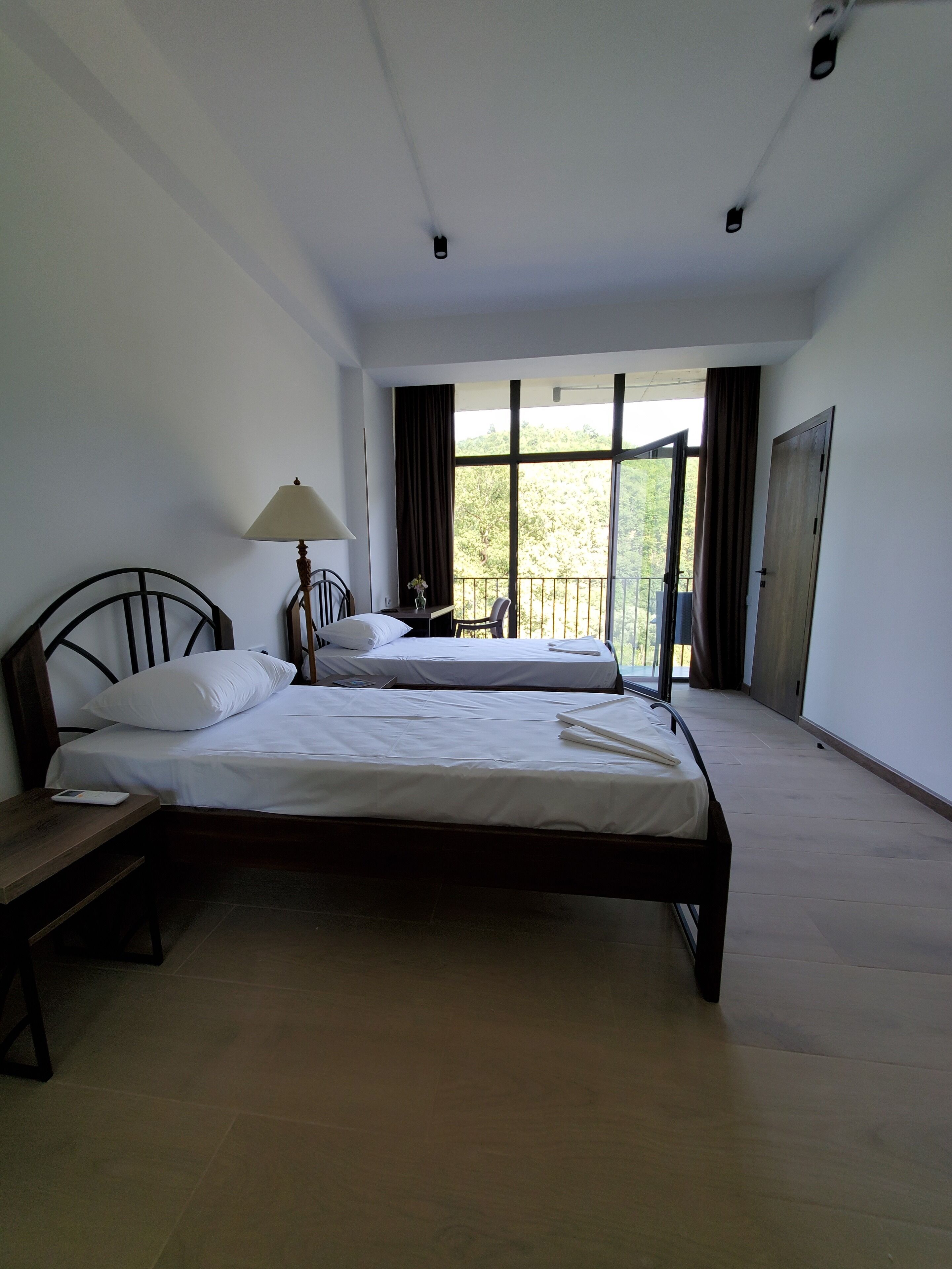 Quarto com duas camas, uma escrivaninha, uma luminária e uma janela com cortinas.