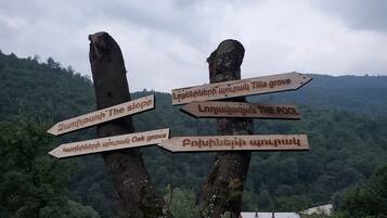 A wooden signpost with multiple directional arrows pointing to various locations such as 'The Slope', 'The Pool', and 'Oak Grove'.