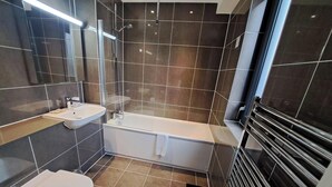 A modern bathroom with a bathtub, toilet, and sink.
