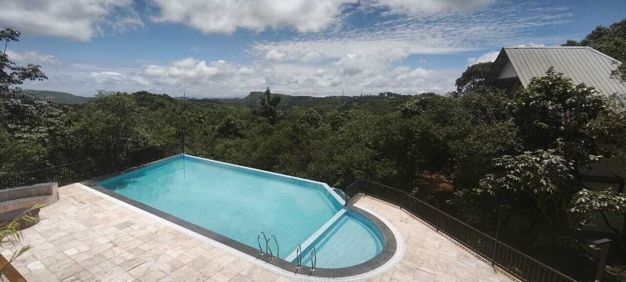 Piscina rectangular con plataforma empaveda, rodeada por una cerca de metal negro.