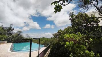 A swimming pool surrounded by lush greenery and a clear sky.