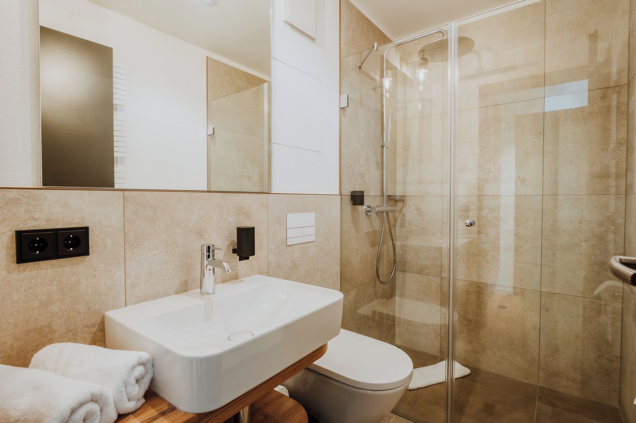 Un bagno con box doccia in vetro, un lavandino bianco e un WC.