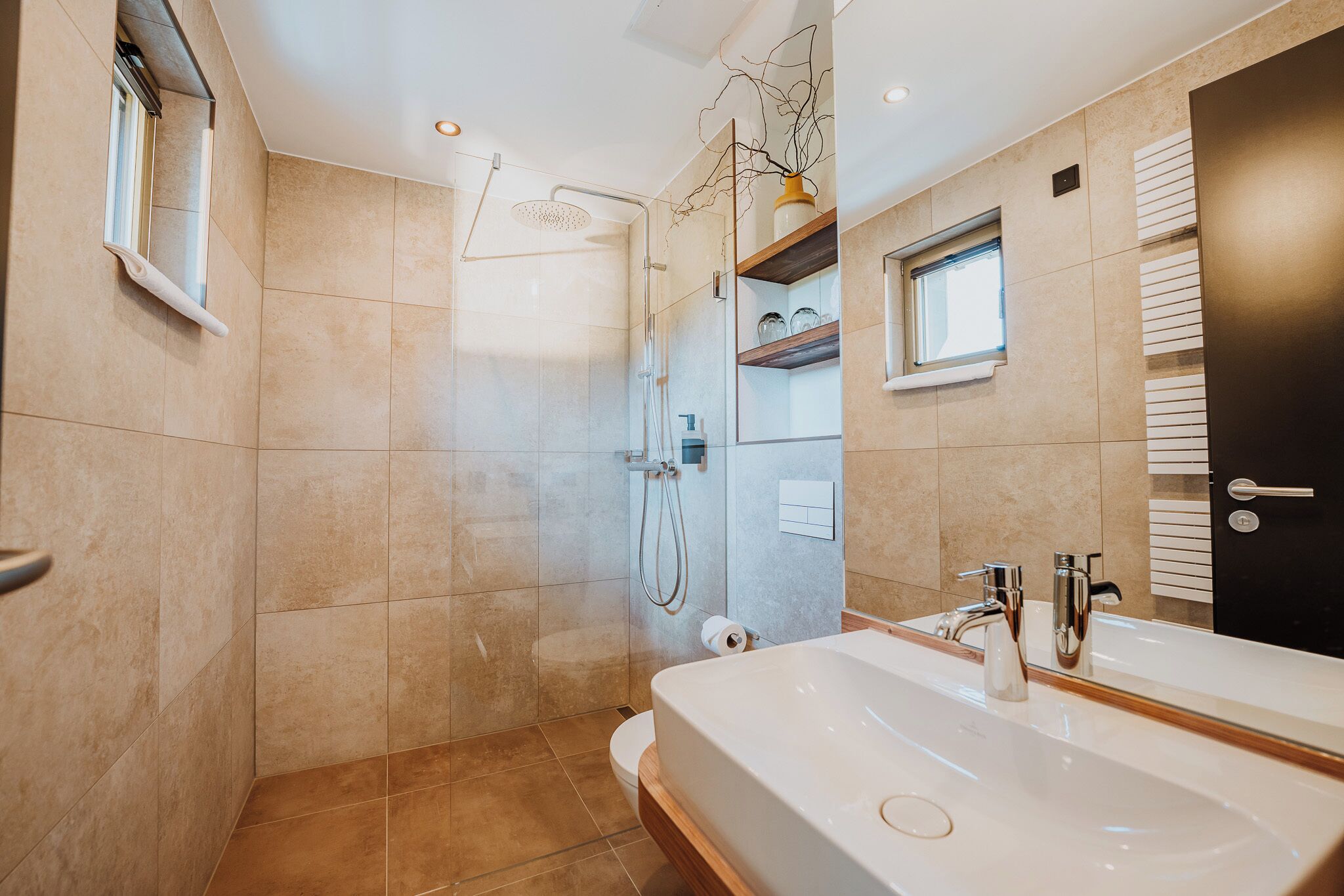 Un baño moderno con ducha, inodoro y un lavamanos grande con espejo.