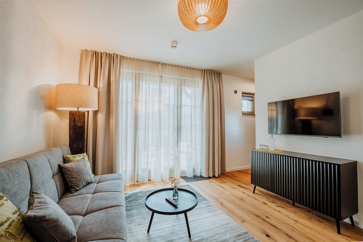 A living room with a sofa, a coffee table, a TV, and a radiator.