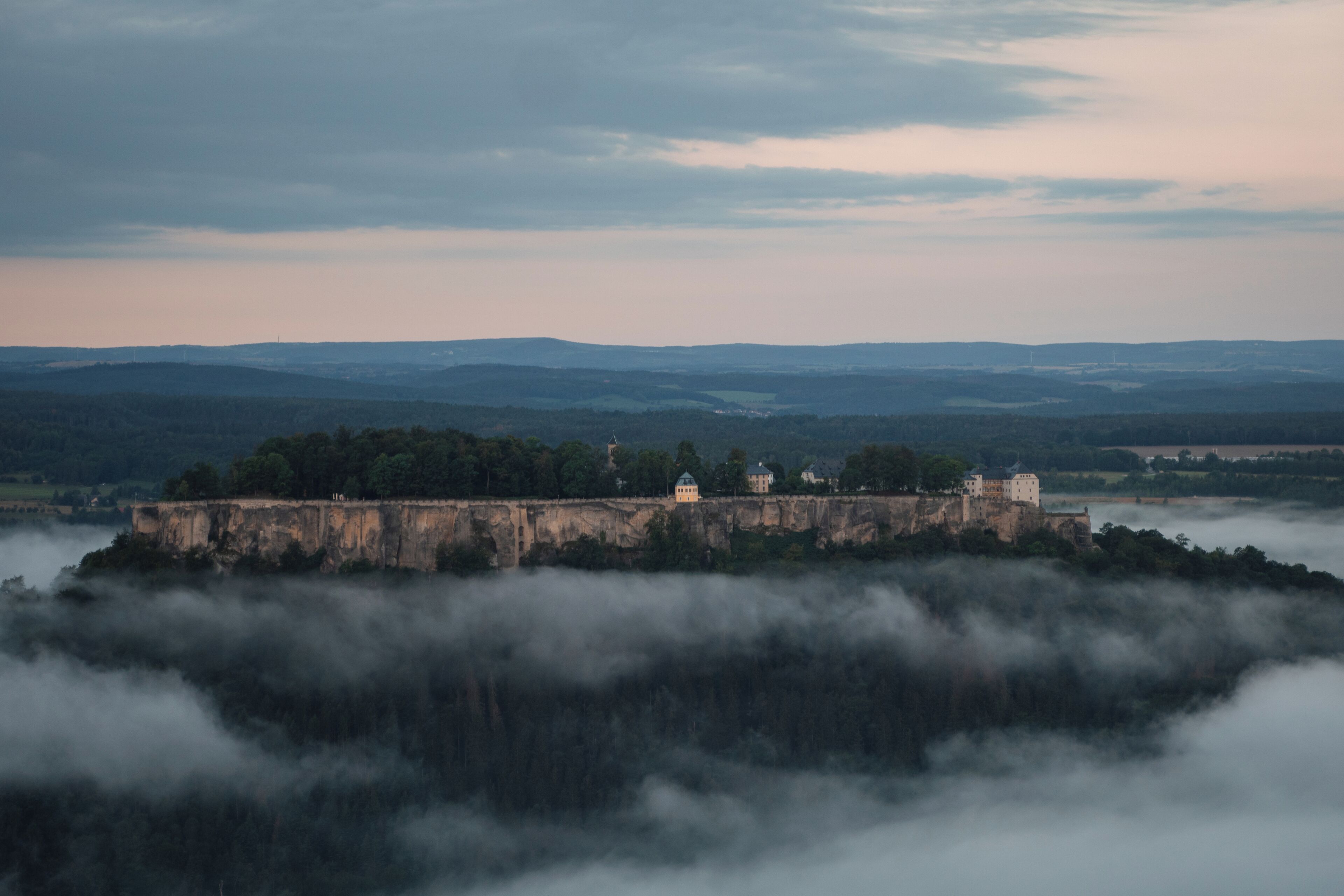A castle on a cliff overlooking a valley.