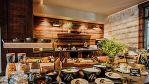 A buffet with various food items, a wooden wall, and a stone wall. - WALDGUT Naturresort (Bad Gottleuba-Berggiesshuebel)