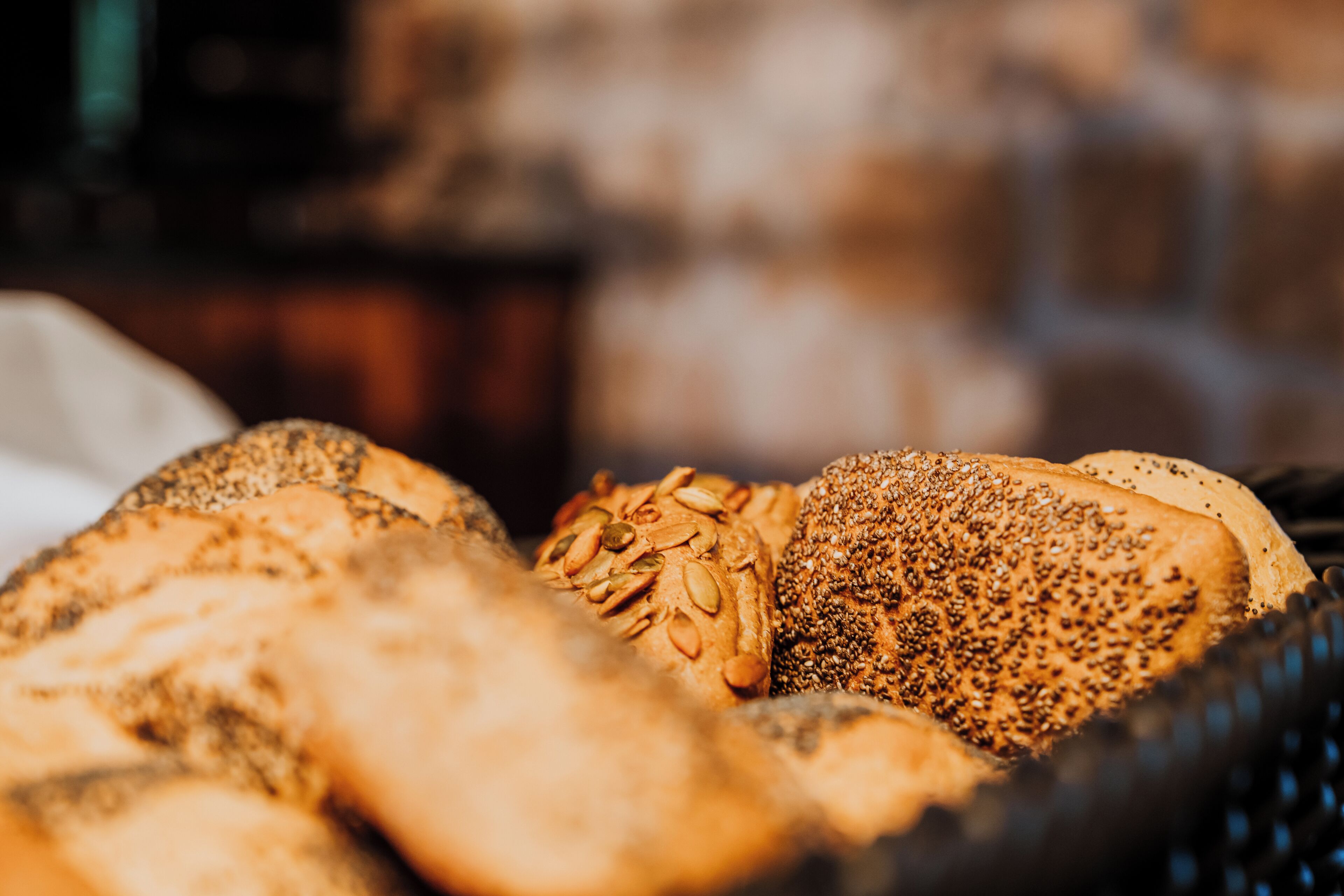 A variety of breads with seeds and grains, displayed in a basket.