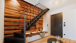 A staircase with wooden paneling, a dark door, and a small table with a vase and glasses. - WALDGUT Naturresort (Bad Gottleuba-Berggiesshuebel)