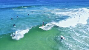 A coastal scene with surfers and waves. - Culloton Escape – Spacious 3BR Family Home Near Parks & Shops (Balga)