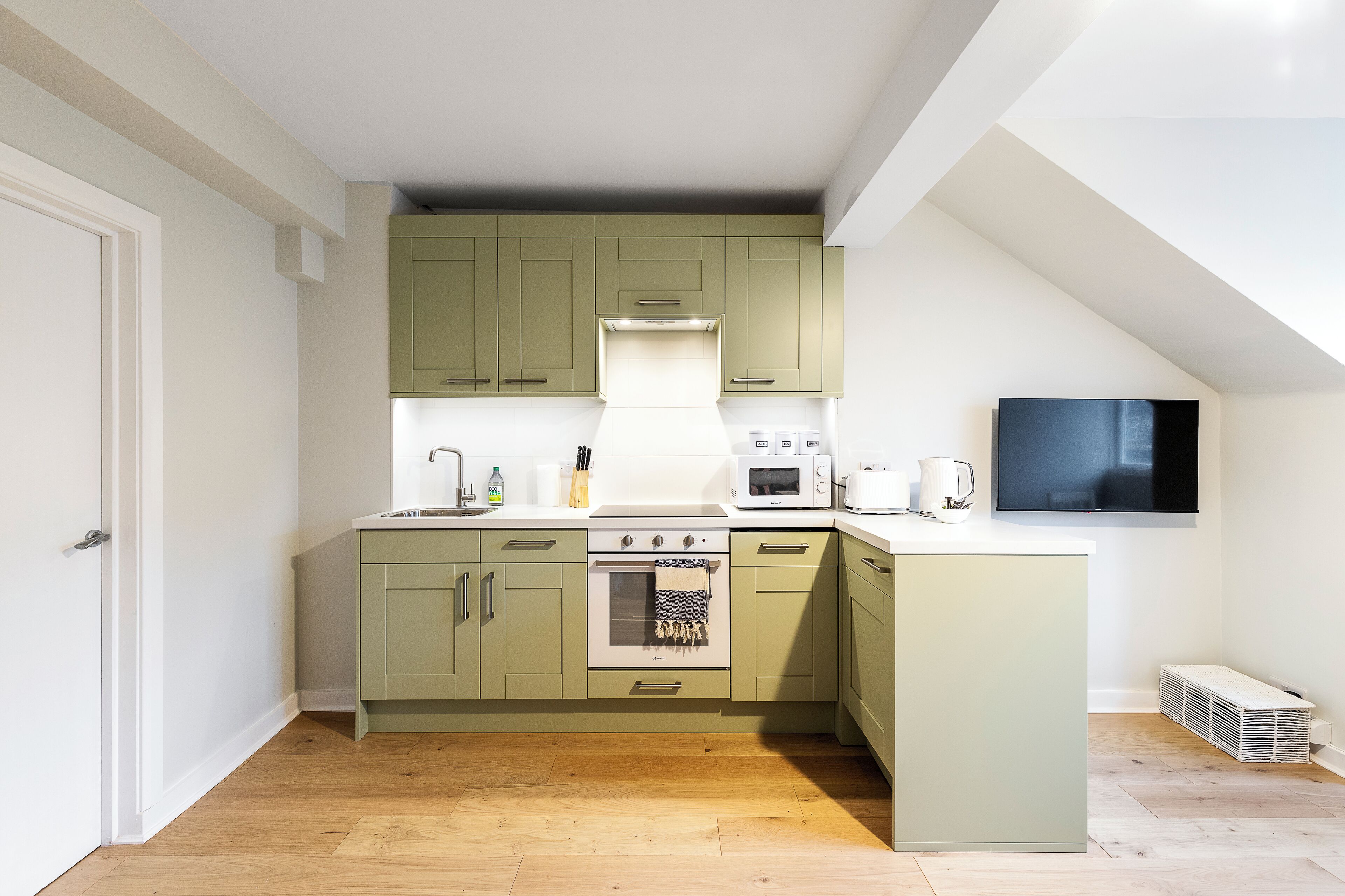A compact kitchen with a built-in oven, microwave, and a small island with a sink.