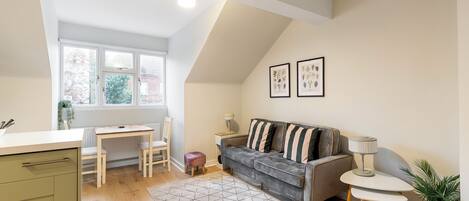 Un espacio habitable compacto con kitchenette, comedor, sofá y una pequeña mesa.