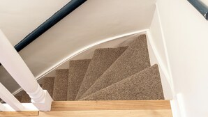 A staircase with a wooden handrail, carpeted steps, and white walls. - Bright and modern East London loft (London)