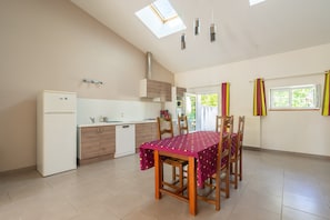 A modern kitchen with a dining table, chairs, and a skylight.