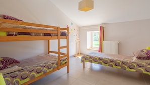 Un dormitorio con literas, una ventana con cortinas, un radiador y una lámpara colgante.