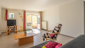 Una sala de estar con televisión, muebles de madera, una silla y un sofá.
