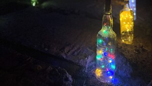 Une rangée de bouteilles illuminées de lumières colorées, posées sur une surface sombre.