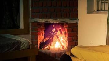 Een kamer met een open haard van baksteen, een bed en een raam met tralies.