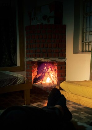 A room with a brick fireplace, a bed, and a window with bars.