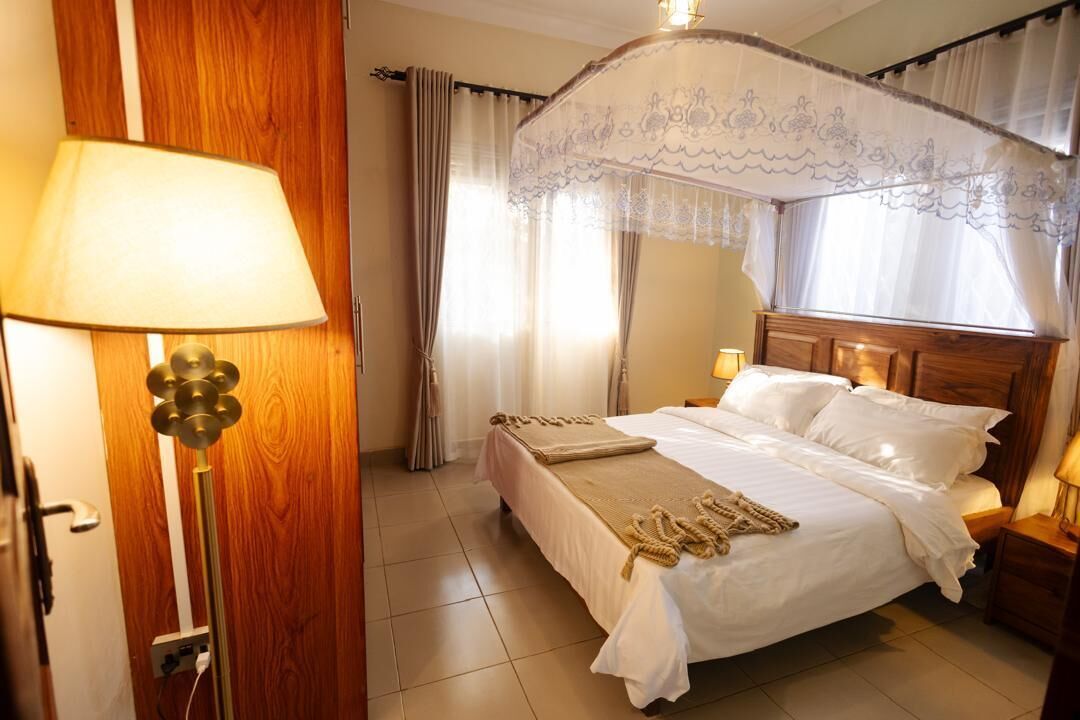 Une chambre à coucher avec un lit, des lampes de chevet, un lit à baldaquin, des rideaux et une porte en bois.