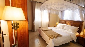 Une chambre à coucher avec un lit, des lampes de chevet, un lit à baldaquin, des rideaux et une porte en bois.