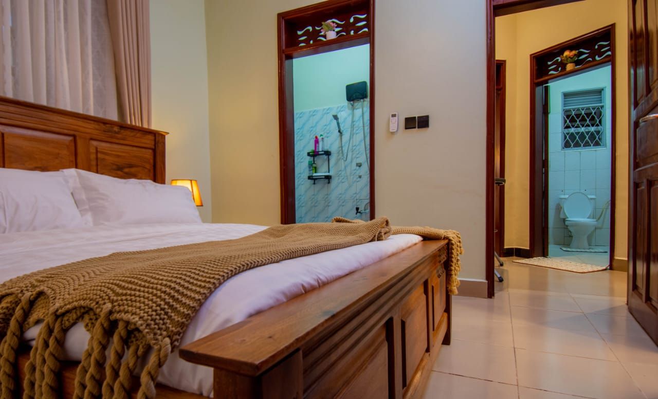 Et hotelværelse med en træseng, badeværelse med bruser og toilet, der ses gennem en åben dør.