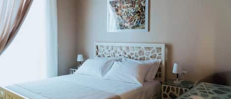 A hotel room with a bed, a nightstand, a lamp, and a painting on the wall.