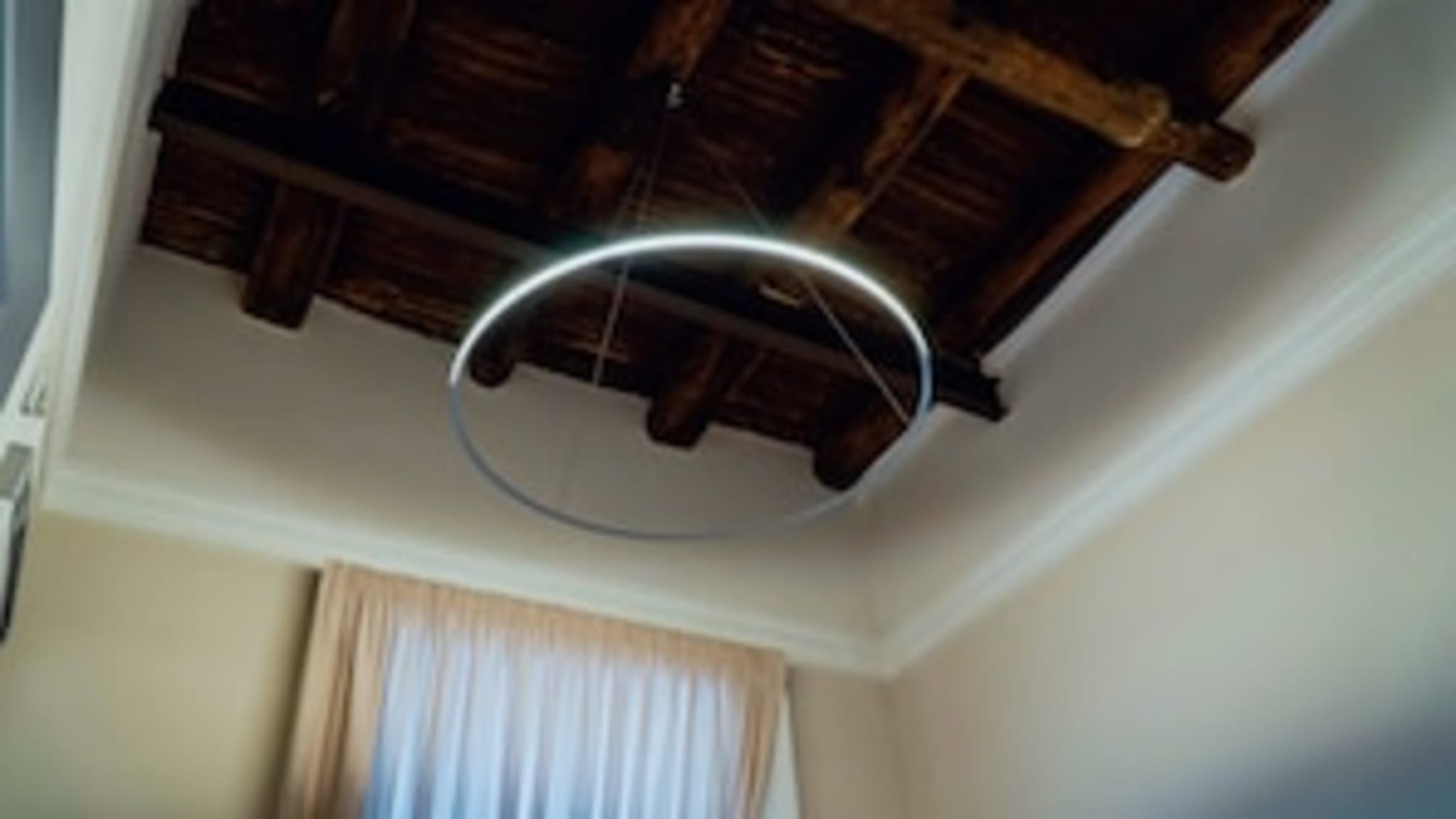 Una stanza con soffitto in legno e lampadario circolare.
