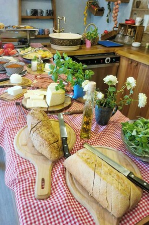 A kitchen with a checkered tablecloth, a loaf of bread, cheese, and various kitchen utensils. - Wellness Hotel Bulgaria (Bansko)
