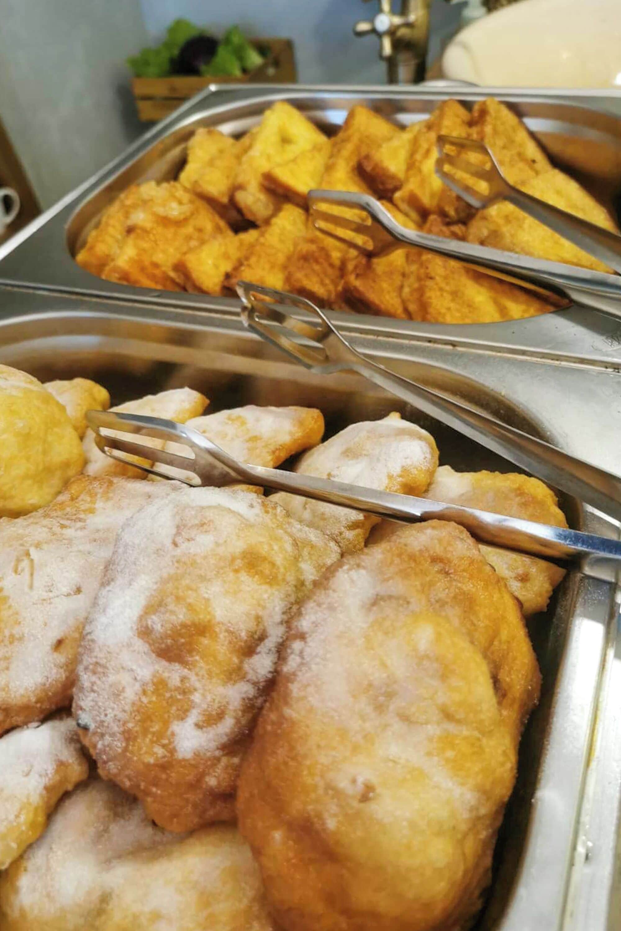 Een buffet met diverse gefrituurde gerechten, waaronder gepaneerde snacks en gebak.