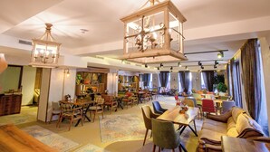 A spacious hotel lobby with a central seating area, multiple dining tables, and a large chandelier. - Wellness Hotel Bulgaria (Bansko)