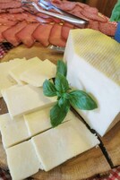 Una tabla de madera con queso y hojas de albahaca.