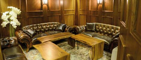 A room with a sectional sofa, wooden coffee table, and wall-mounted lighting.