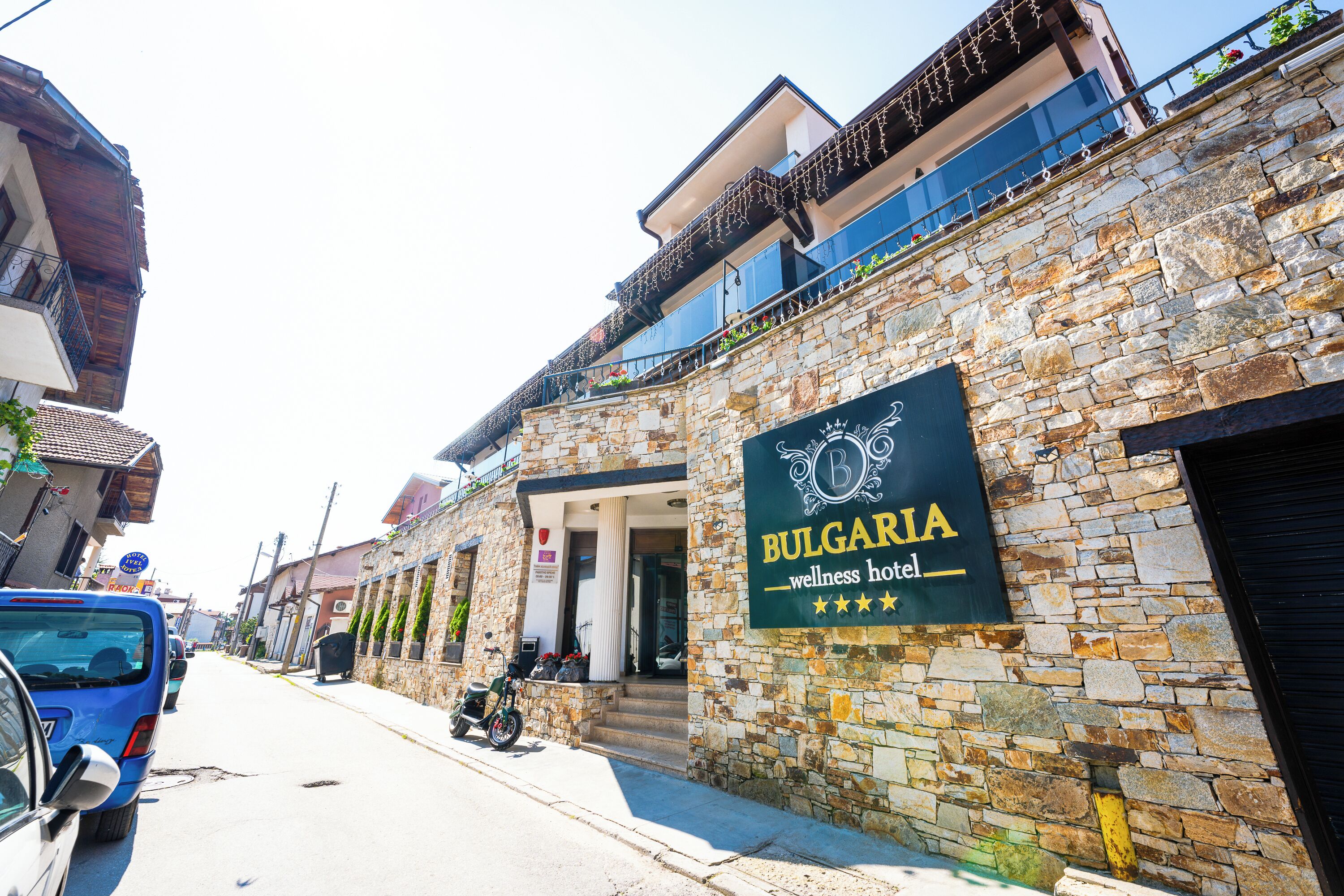 Ein Steinhaus mit einem Schild für 'Bulgaria Wellness Hotel', das einen Balkon mit Pflanzen zeigt.