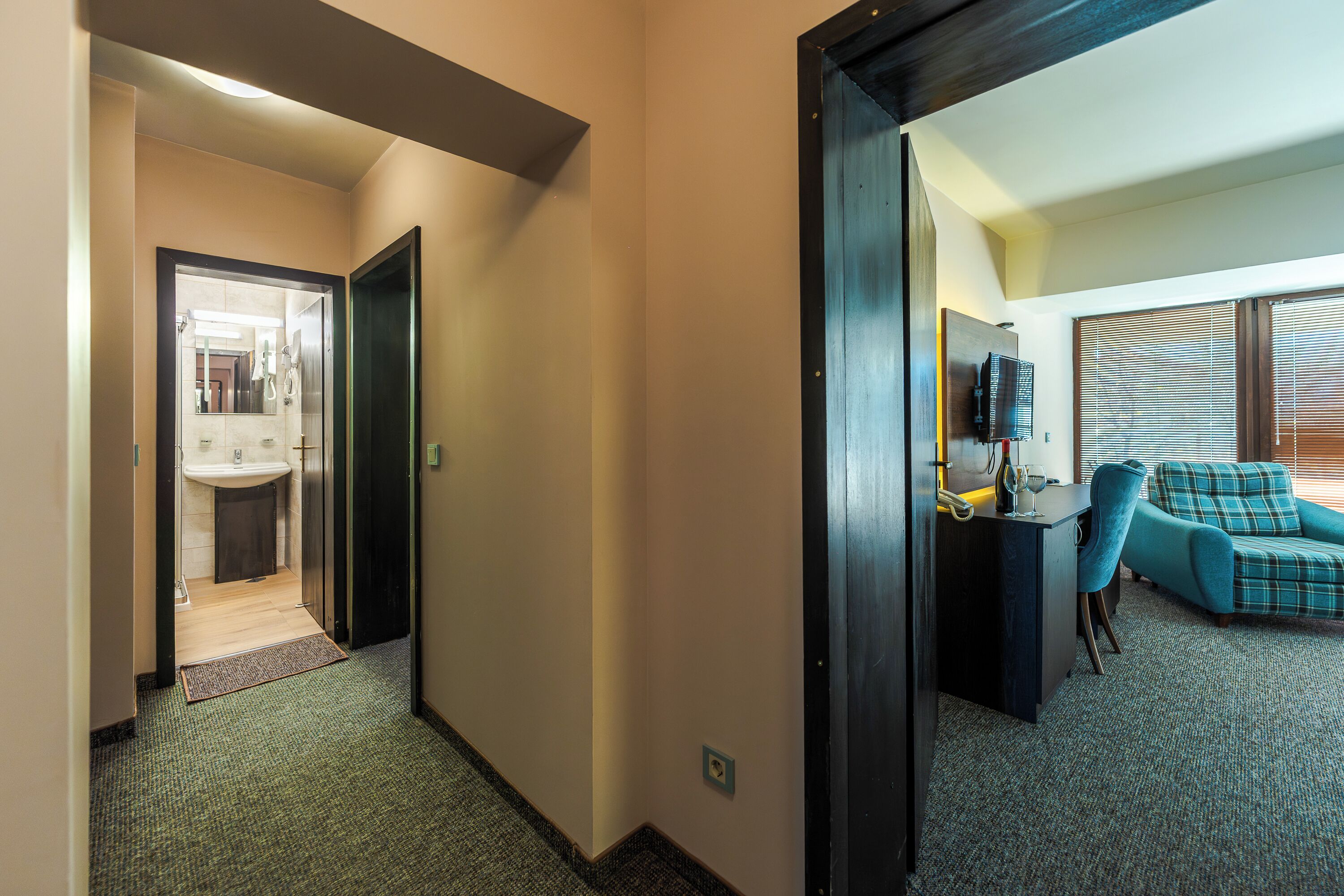 Una habitación de hotel con baño, escritorio, silla y sofá.
