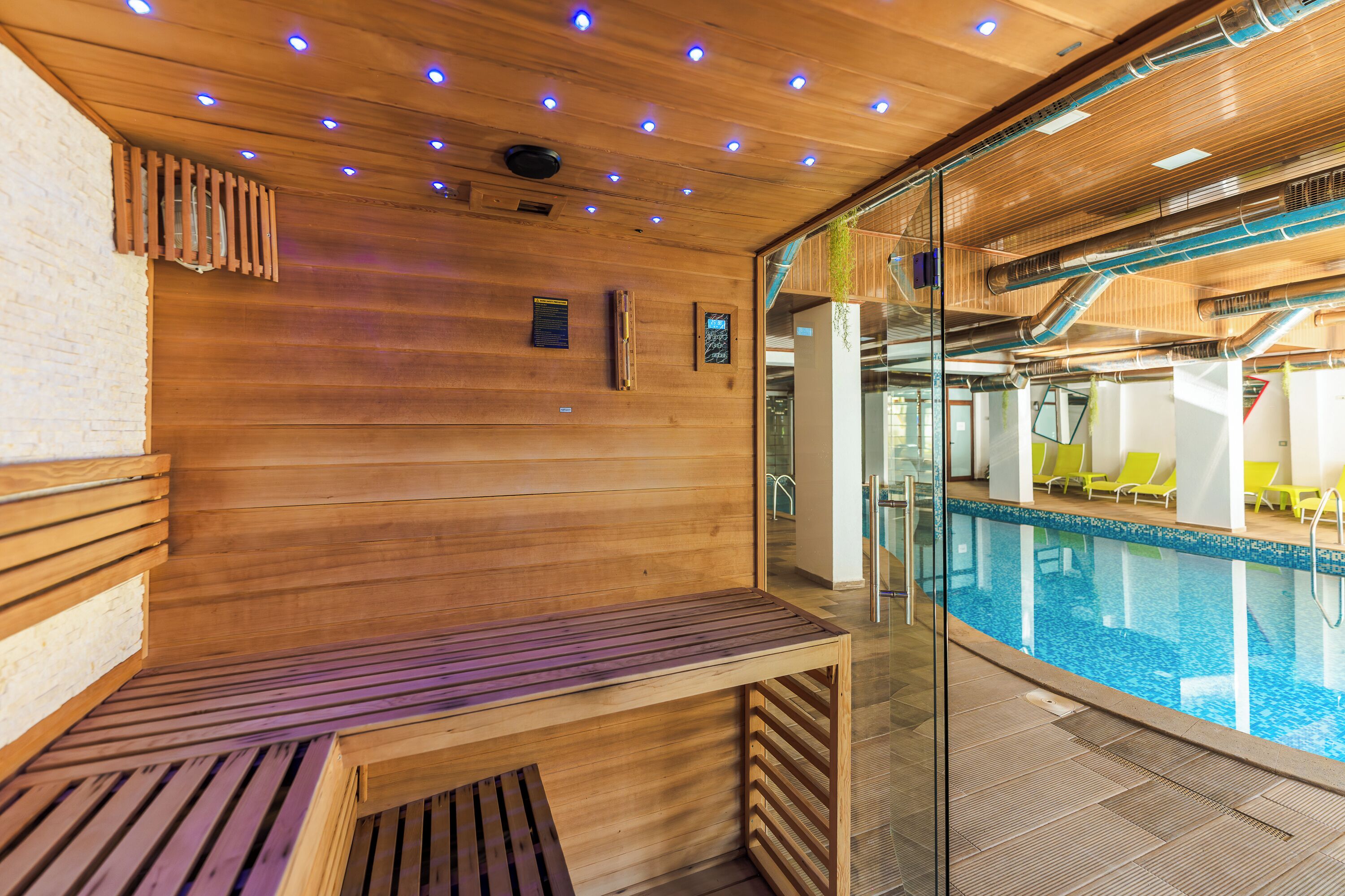 A wooden interior with a pool area, including a bench and lounge chairs.